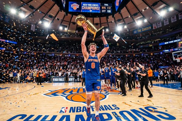 New York Knicks player #8 holds the championship trophy at Madison Square Garden as confetti falls after a title win